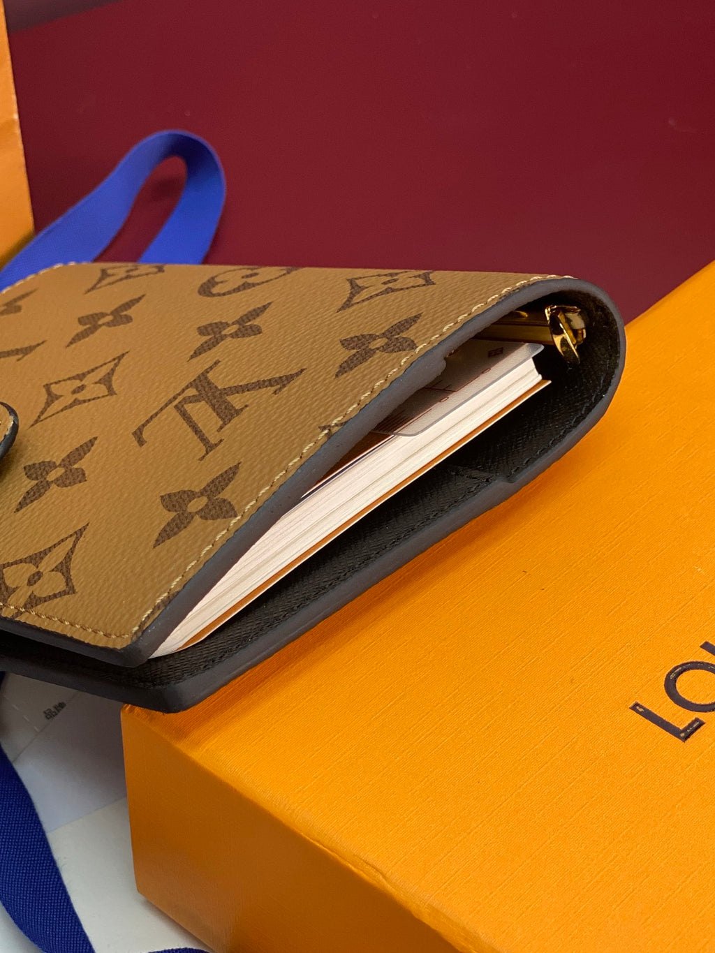 Small leather bag with monogram pattern, blue strap, open top showing card slot