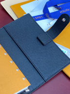 Louis Vuitton small bag, textured blue planner cover with strap loop and stitching