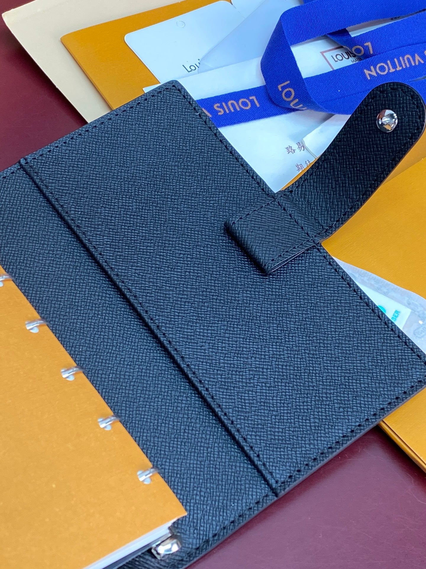Louis Vuitton small bag, textured blue planner cover with strap loop and stitching