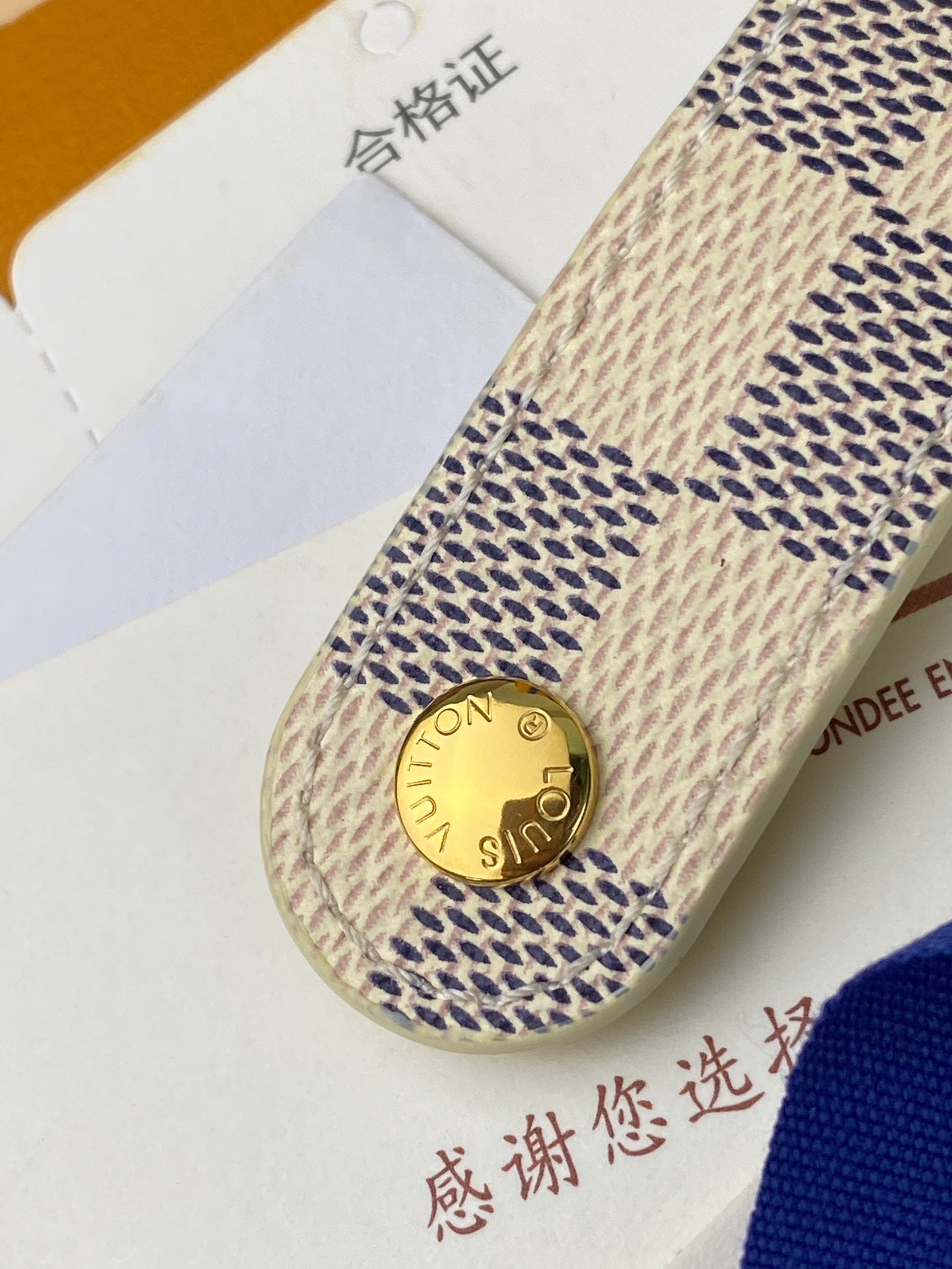 Small bag end tab with gold snap button and stitched patterned fabric strap