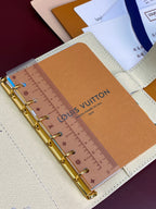 Close-up of ivory agenda cover showing ruler insert and gold ring binder