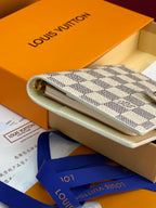 Small patterned clutch-style bag with light strap, partially inside a box