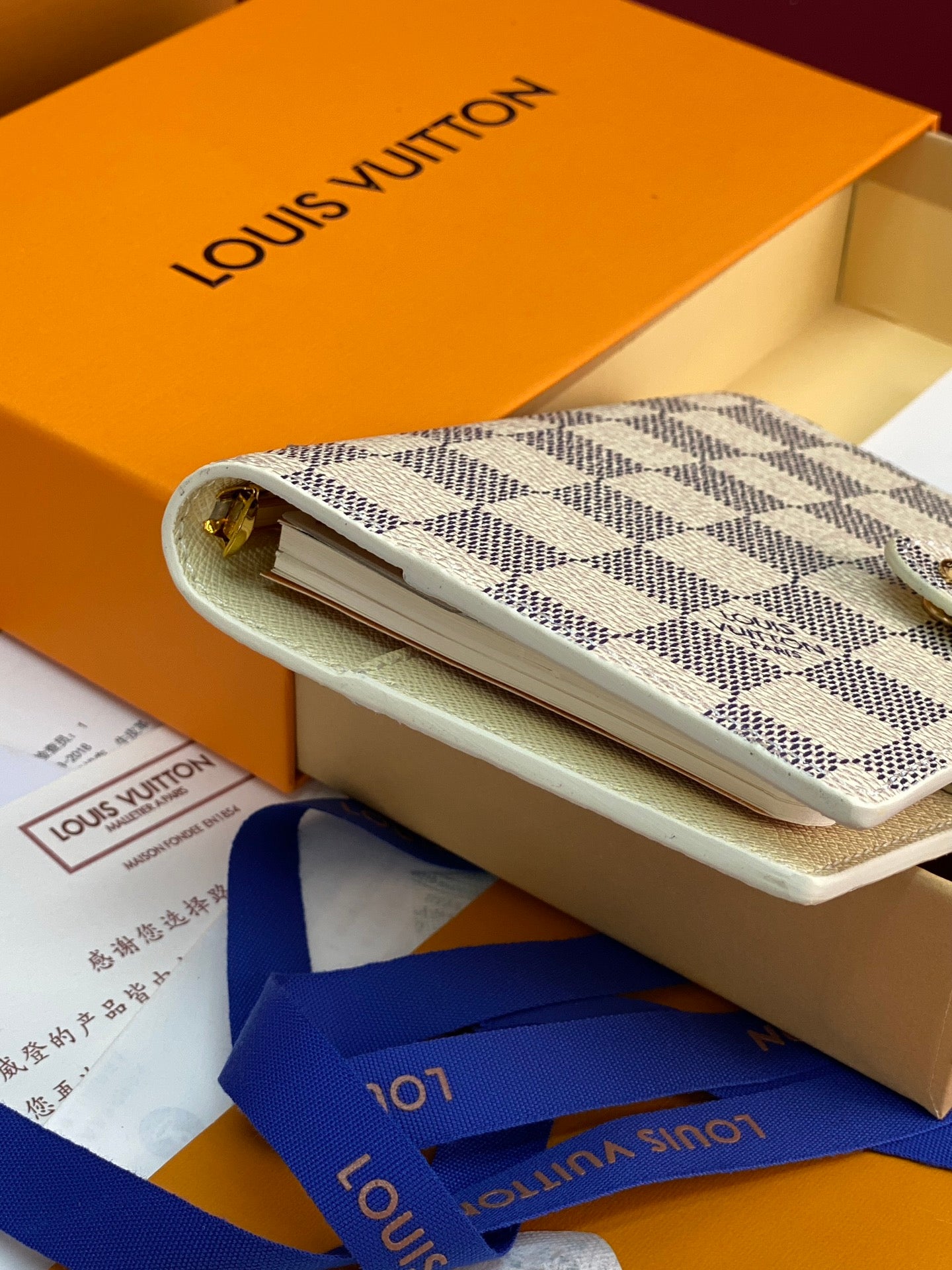 Small patterned clutch-style bag with light strap, partially inside a box