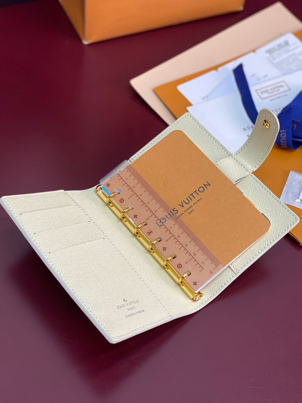 Ivory agenda cover with ring binder, tan panel label, and gold-tone hardware