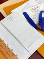 Small bag open with stitched grid panel and monogram text on the light cover.