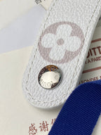 Small bag close-up: white textured leather with round clasp and monogram patch, pink tint.