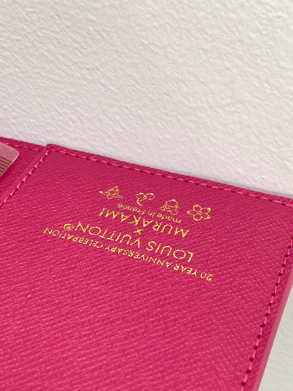 Small bag close-up of magenta leather with Louis Vuitton logo stamp and flower emblem