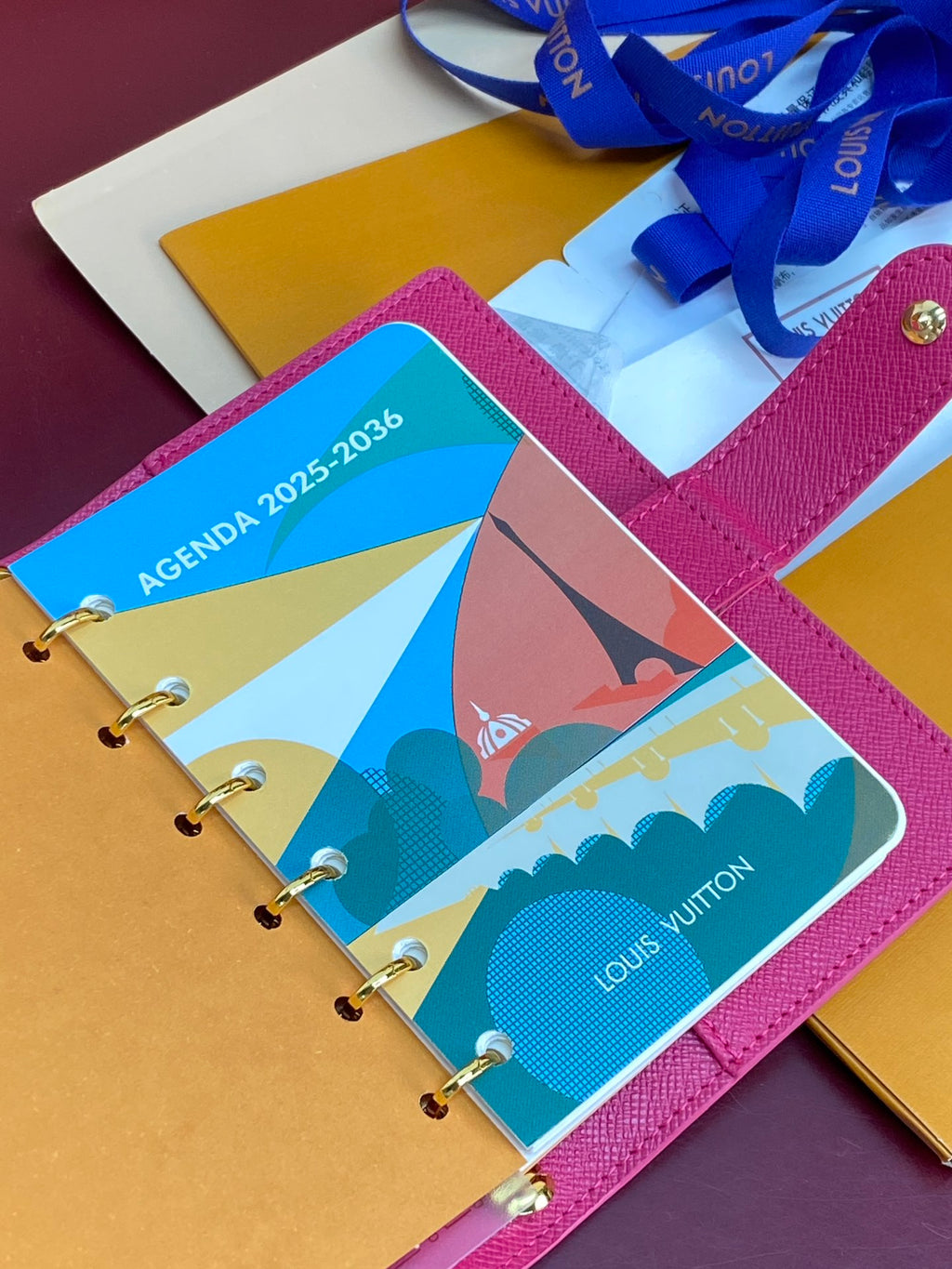 Small bag planner with magenta cover and colorful agenda inserts on metal rings