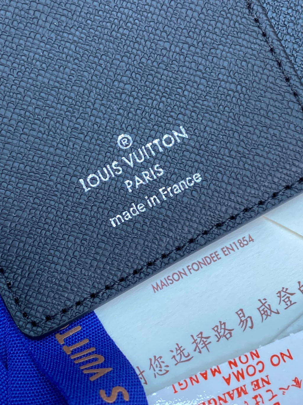 Louis Vuitton small bag close-up of embossed logo, text, and edge stitching