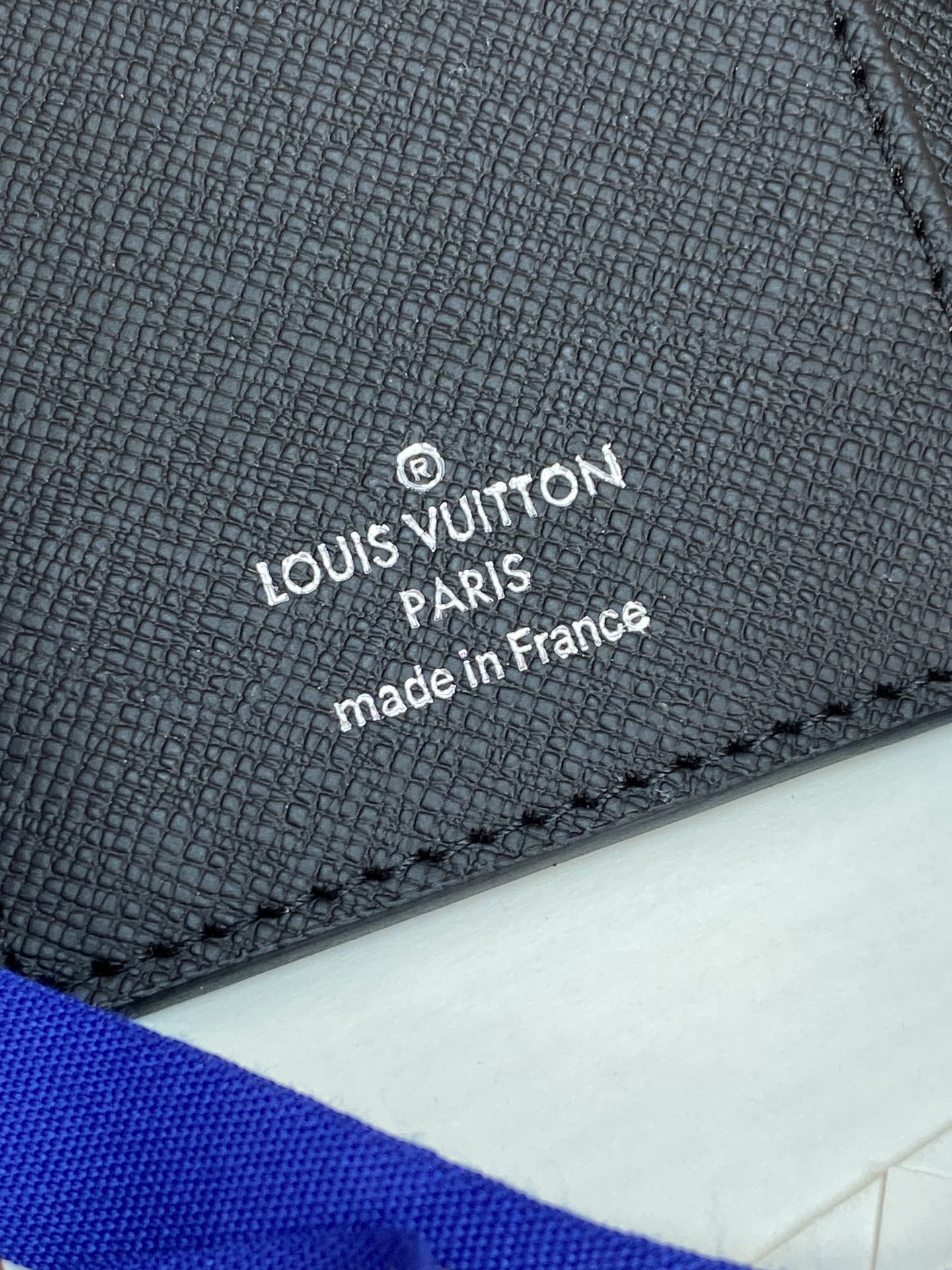 Louis Vuitton small bag interior label, black textured leather with “made in France” text.