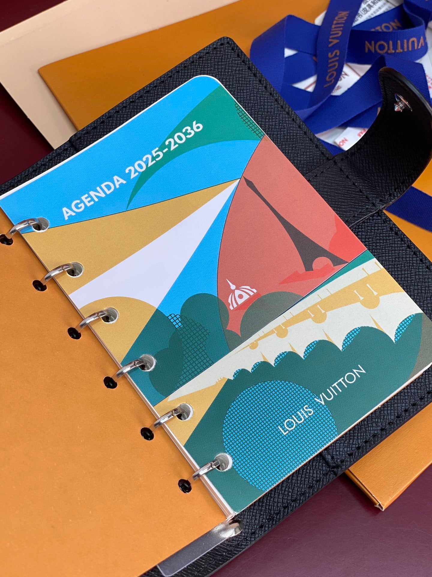 Louis Vuitton small bag open, featuring colorful agenda inserts with ring binder pages.