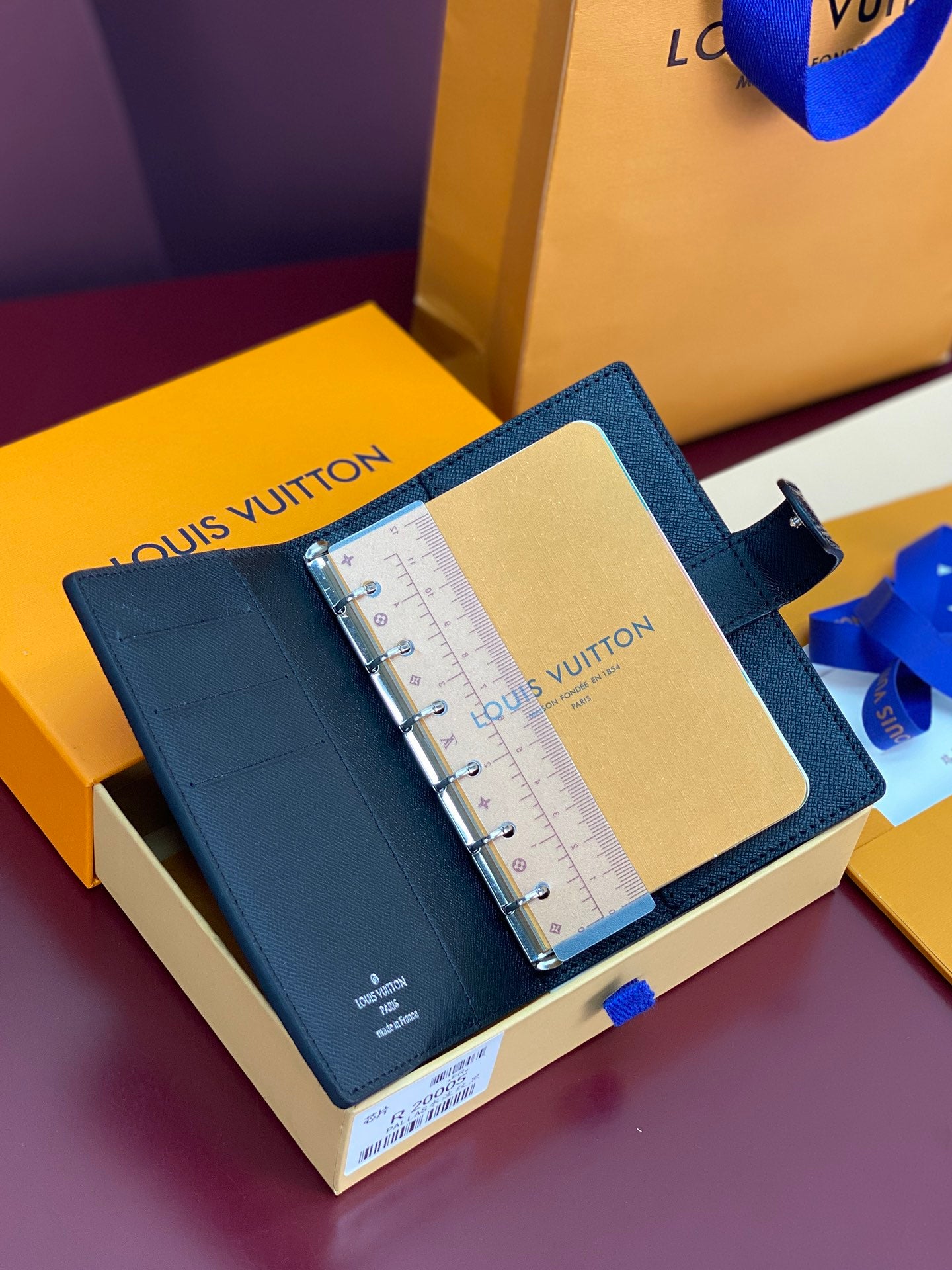 Louis Vuitton small bag open, showing inside pocket and planner ruler insert in blue.