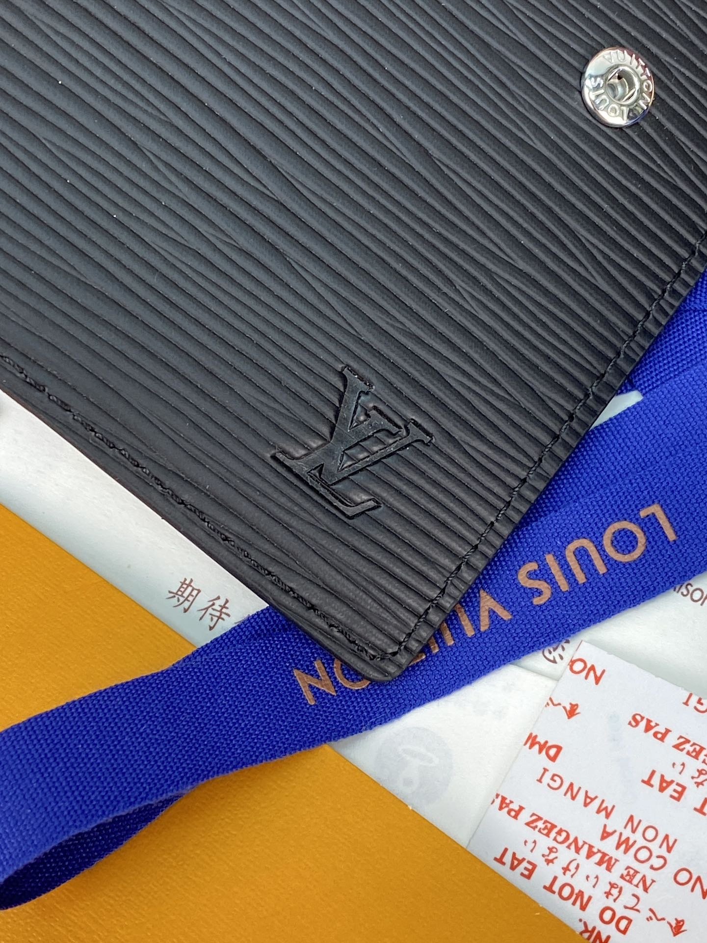 Small bag with black textured finish and embossed logo, plus blue web strap