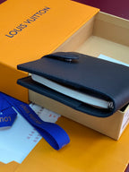 Small bag with dark navy foldover flap and snap button, shown in a box