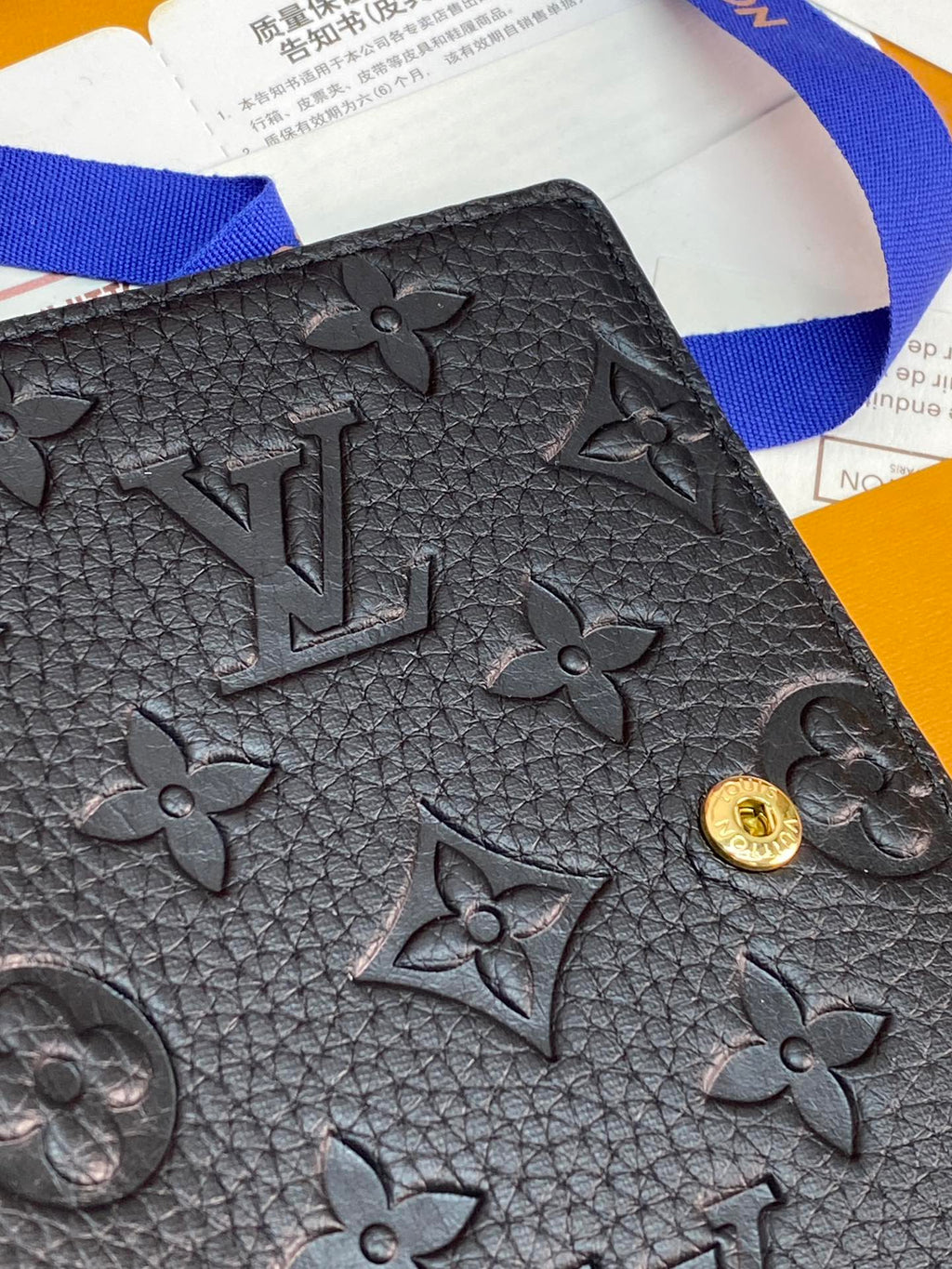 Black textured leather small bag with embossed monogram flowers and gold clasp button