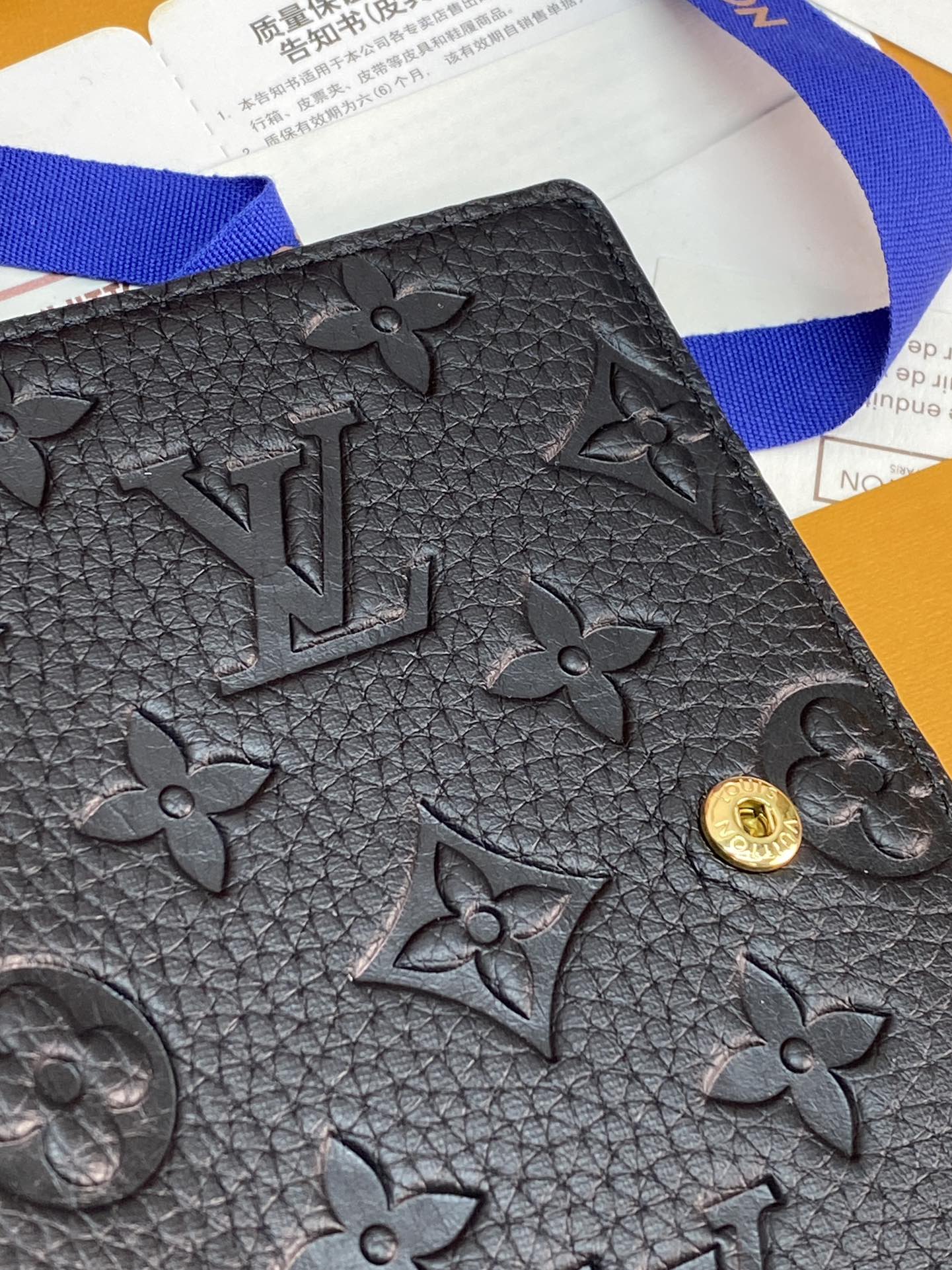 Black textured leather small bag with embossed monogram flowers and gold clasp button