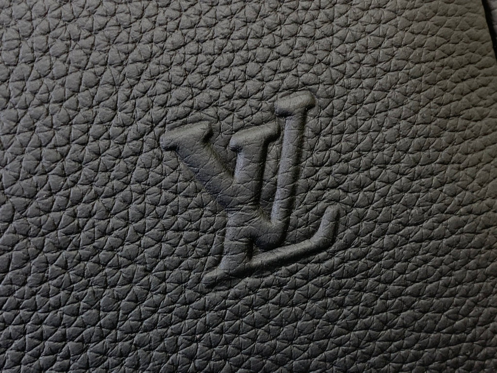 Louis Vuitton leather bag logo mark embossed on dark textured surface