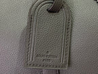Louis Vuitton leather bag close-up with stitched logo patch on front