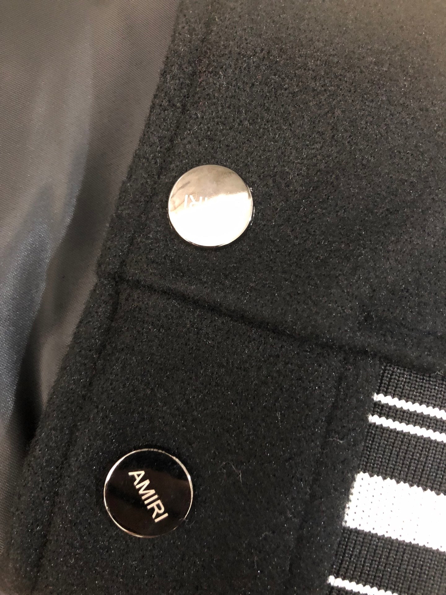 Black jacket with metal snap buttons and ribbed striped cuff detail