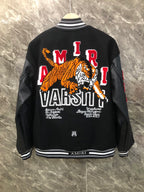 Black varsity jacket back with large tiger graphic and embroidered AMIRI text