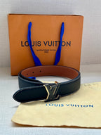 Louis Vuitton leather belt, dark navy strap with gold LV buckle and brown leather keeper.