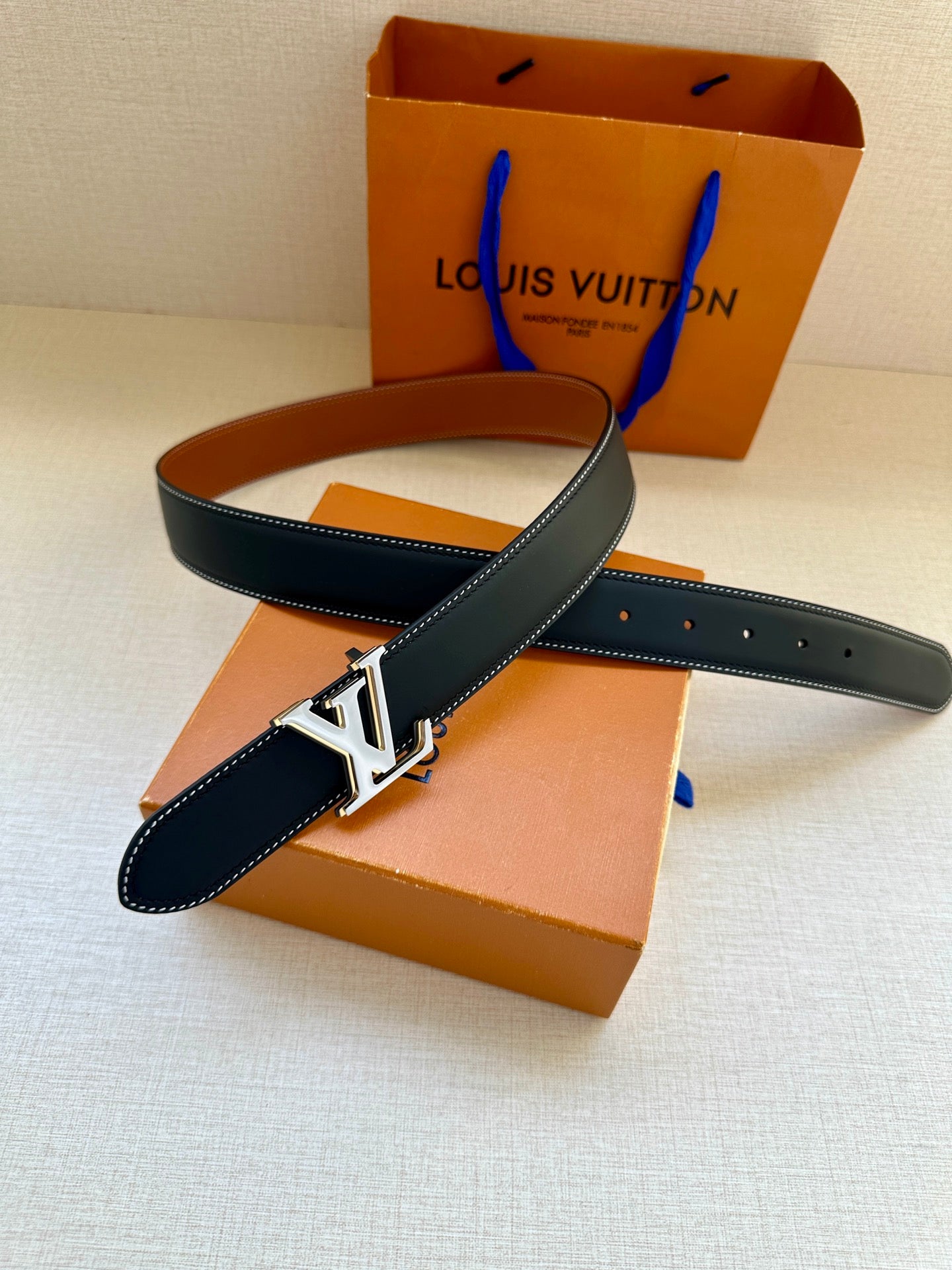 Leather belt with navy strap, tan underside, and gold LV buckle