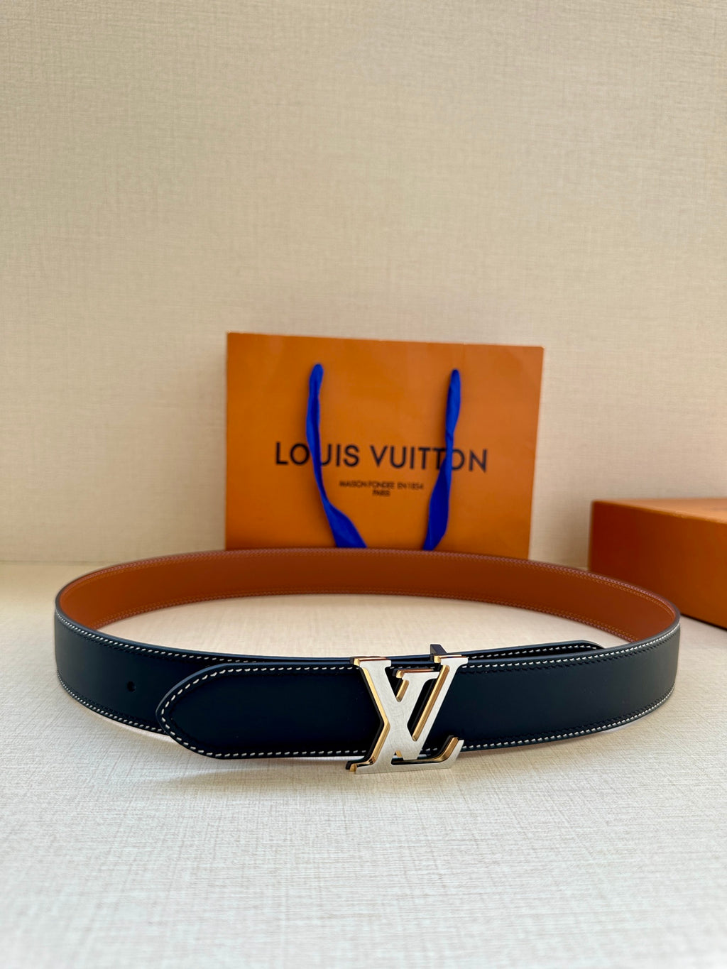 Leather belt with dark navy strap, tan lining, and gold LV buckle
