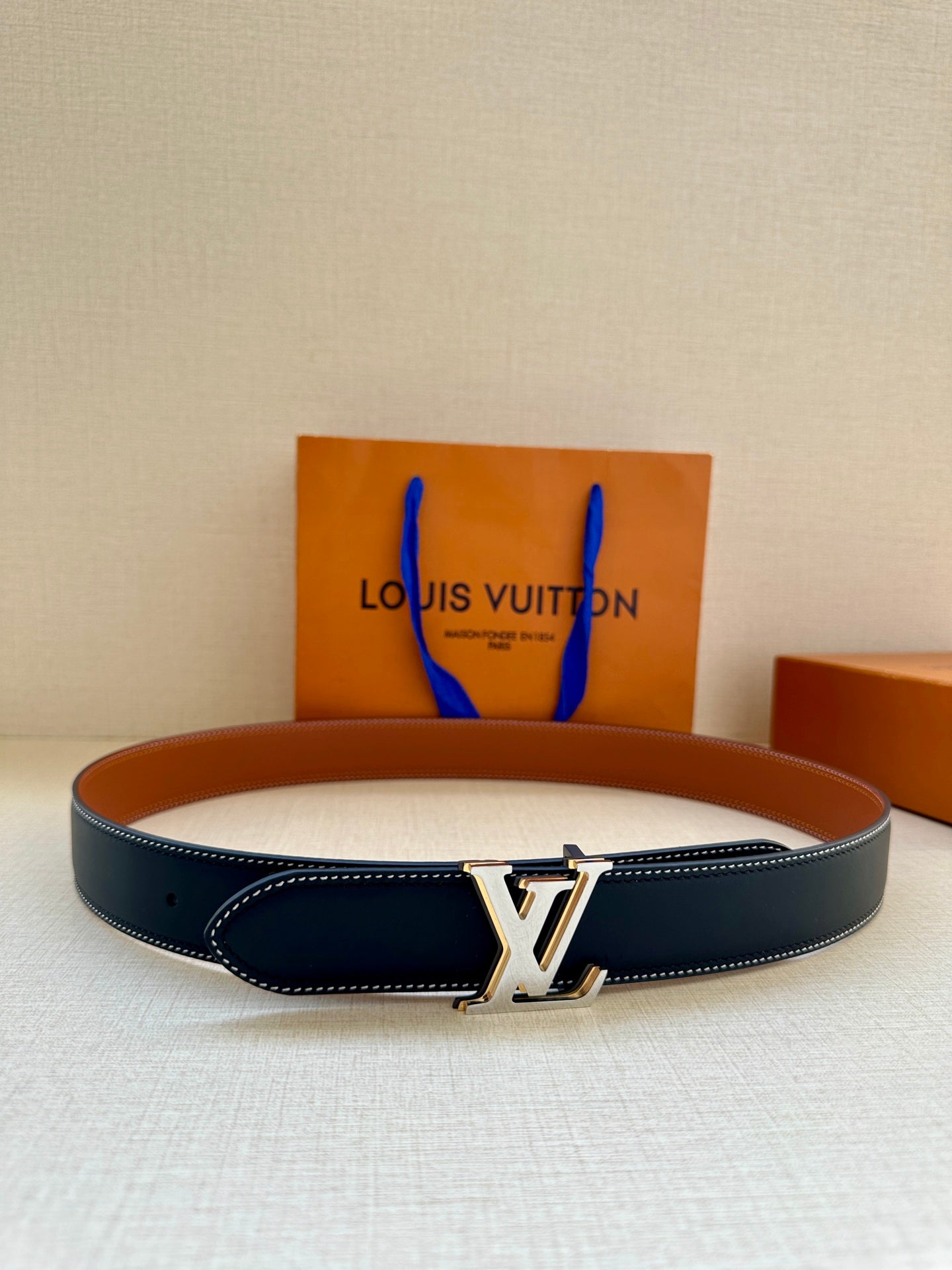 Leather belt with dark navy strap, tan lining, and gold LV buckle