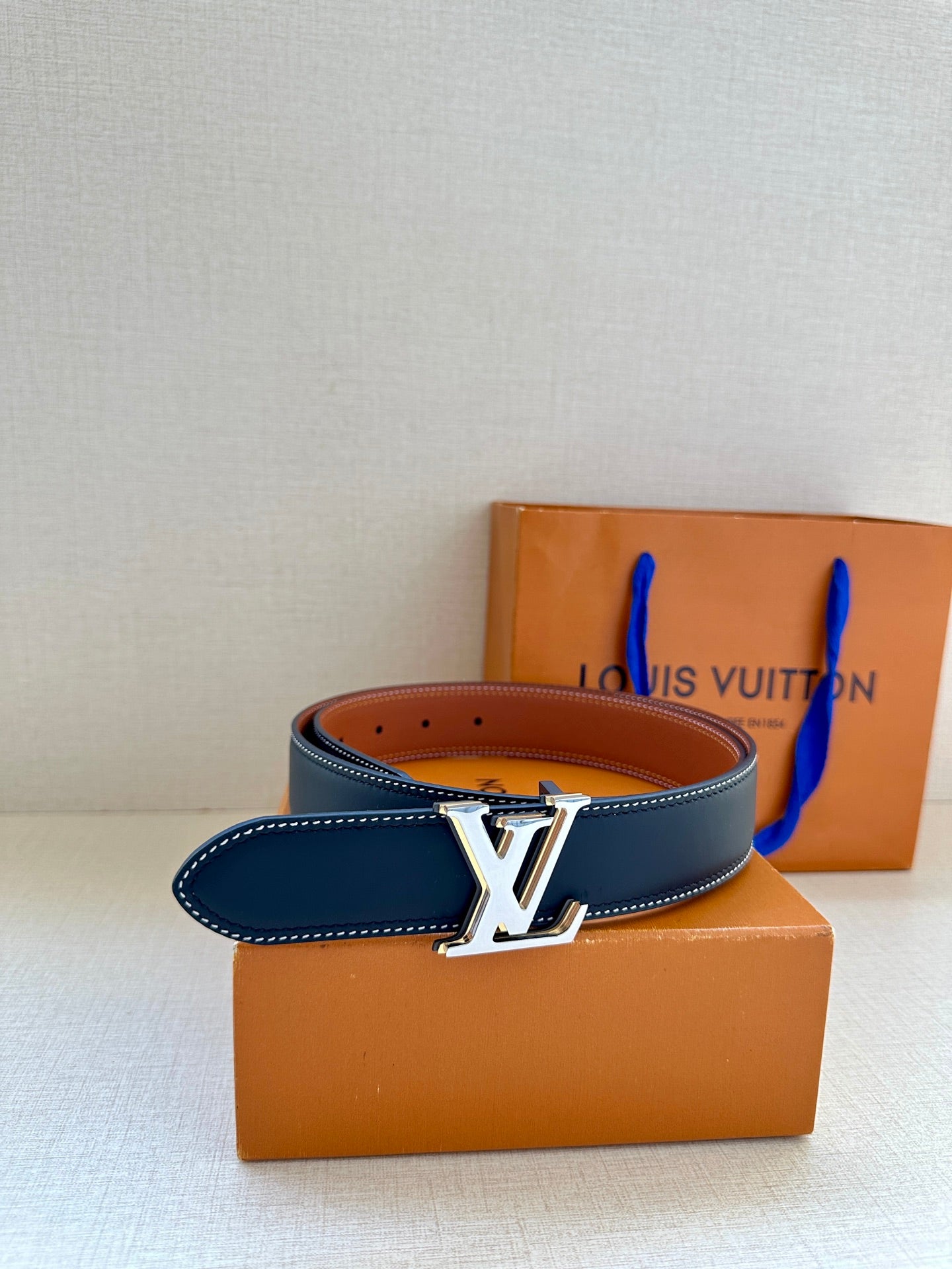 Leather belt with dark navy strap, white edge stitching, and gold LV buckle