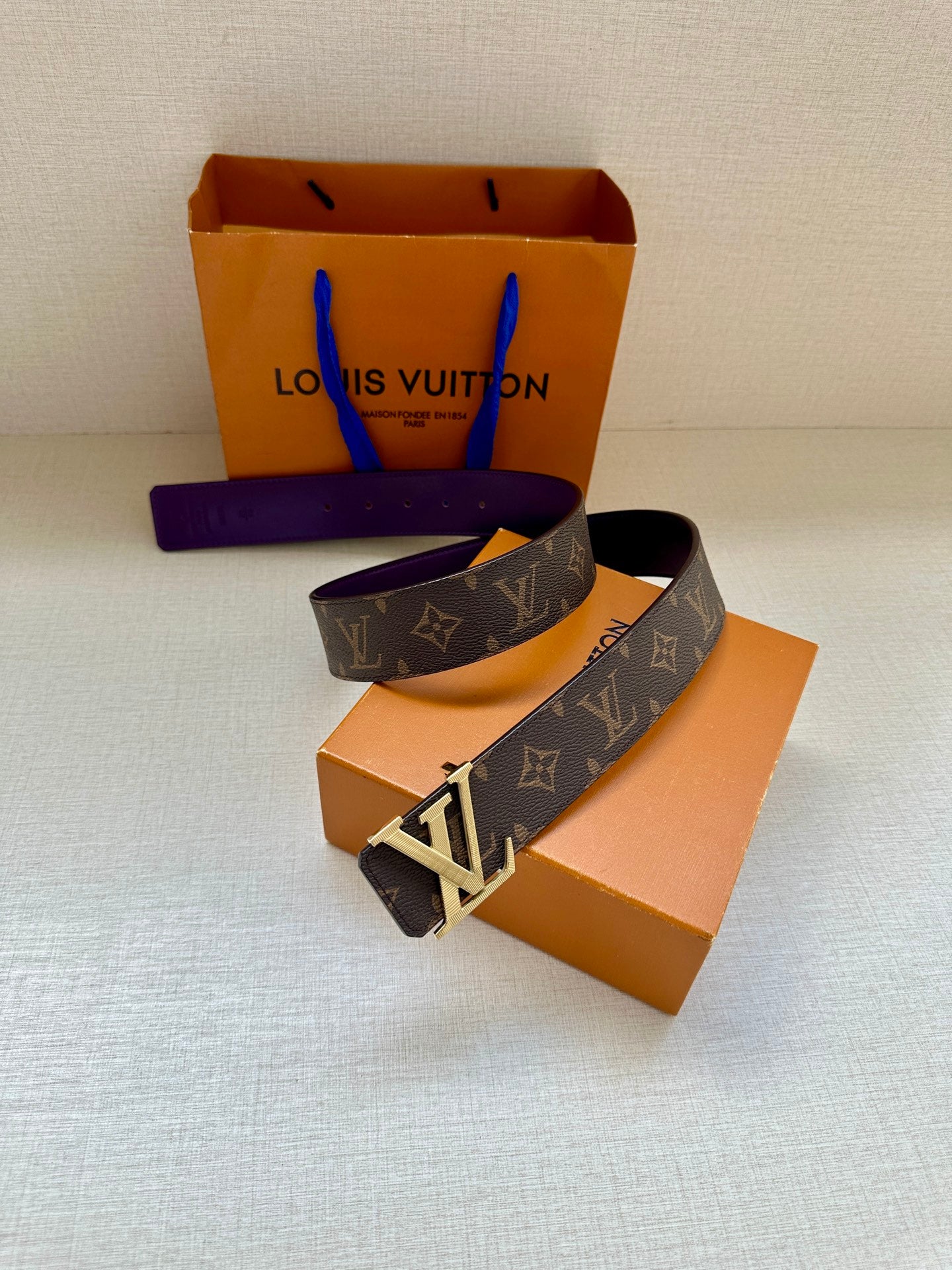 Monogram belt with purple strap and gold LV buckle, angled view