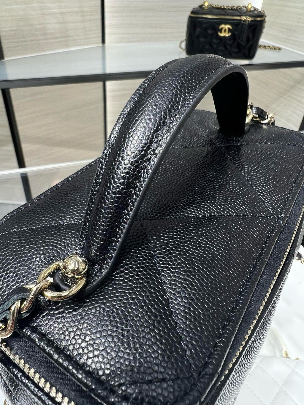 Chanel bag detail with chain strap, dark pebbled leather texture and gold hardware
