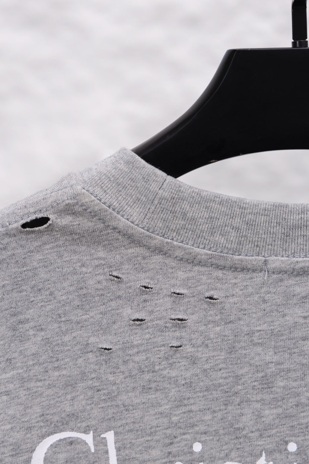 Dior long-sleeve crewneck top close-up at shoulder seam, heather gray with small distress holes