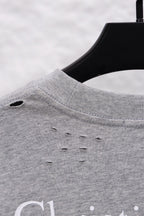 Dior long-sleeve crewneck top close-up at shoulder seam, heather gray with small distress holes