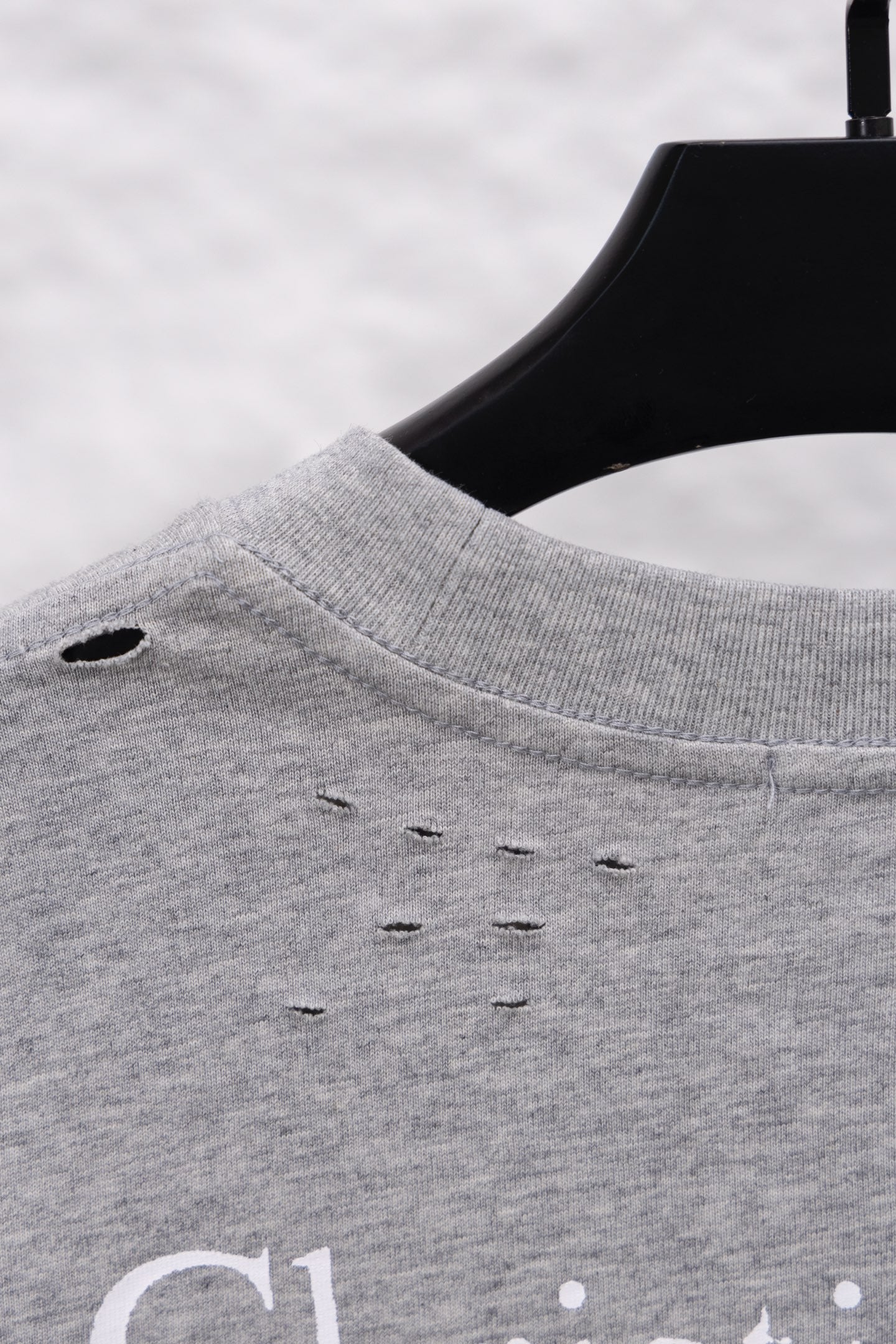 Dior long-sleeve crewneck top close-up at shoulder seam, heather gray with small distress holes