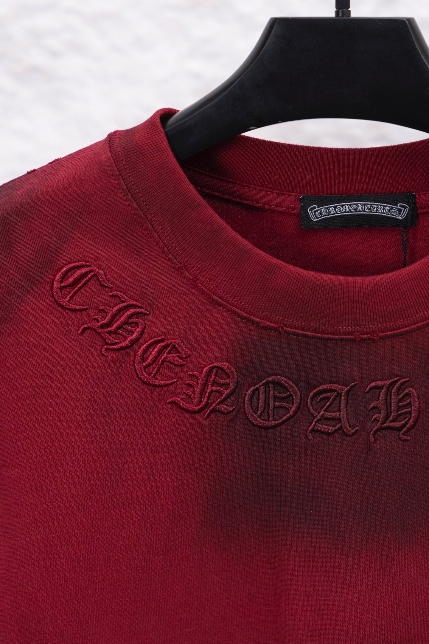Red long-sleeve shirt closeup of ribbed collar and embroidered script logo