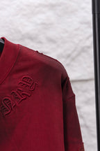 Red long-sleeve shirt closeup of side embroidery on sleeve