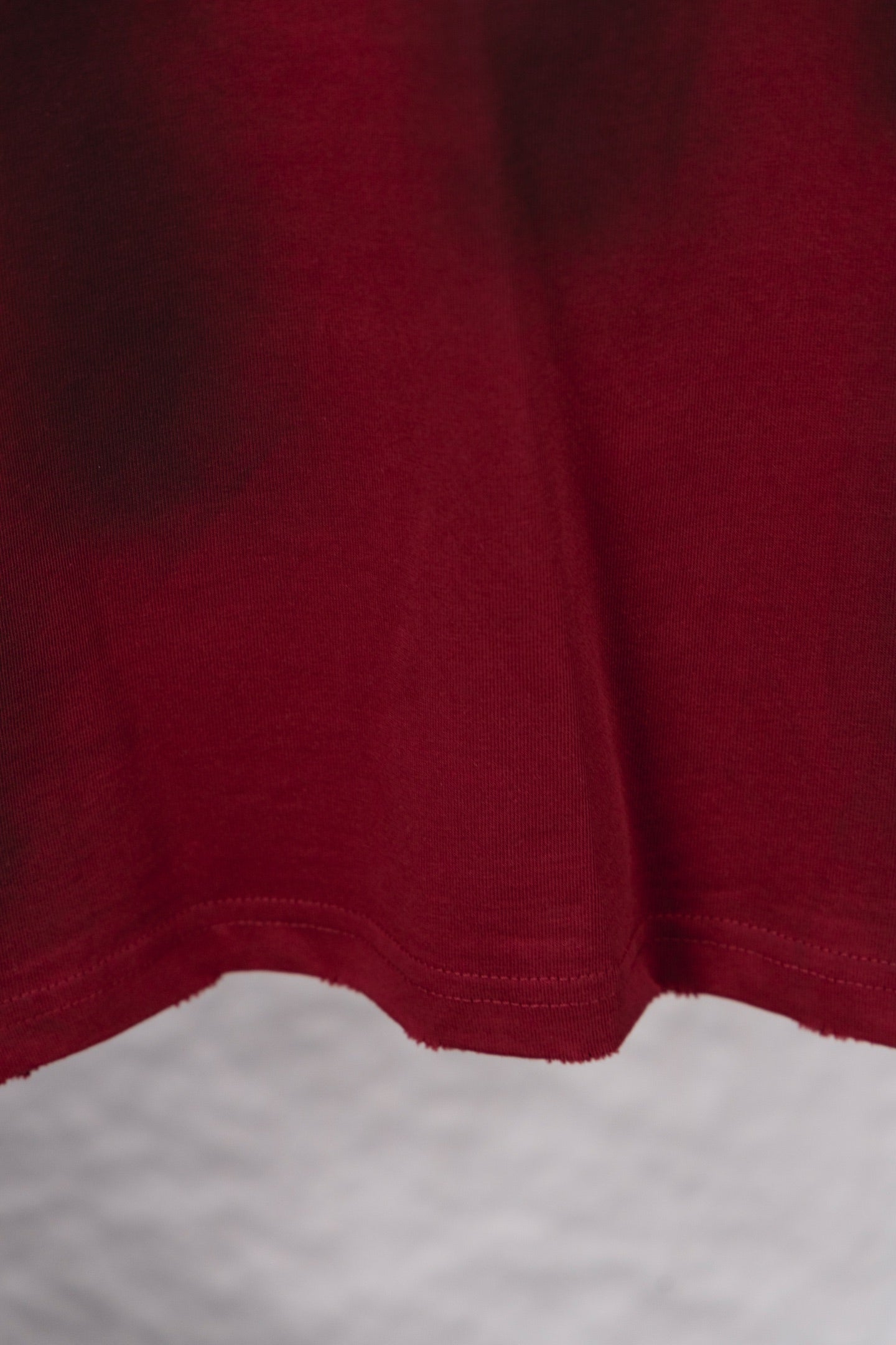 Red long-sleeve shirt with straight hem and visible seam stitching at bottom