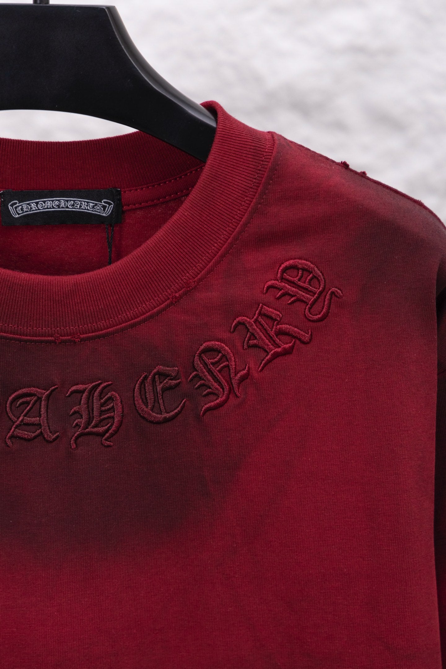 Red long-sleeve shirt closeup, neckline with stitched dark script logo