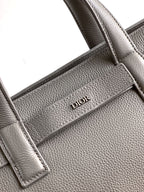 Dior men’s light gray leather bag close-up of logo-embossed center strap panel