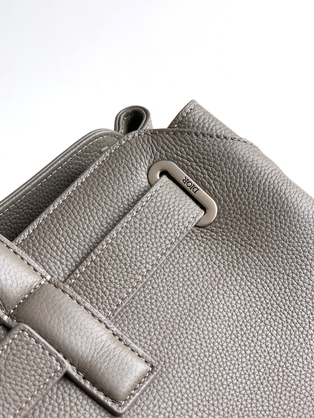 Dior men’s light gray leather bag close-up of metal D-ring and strap detail