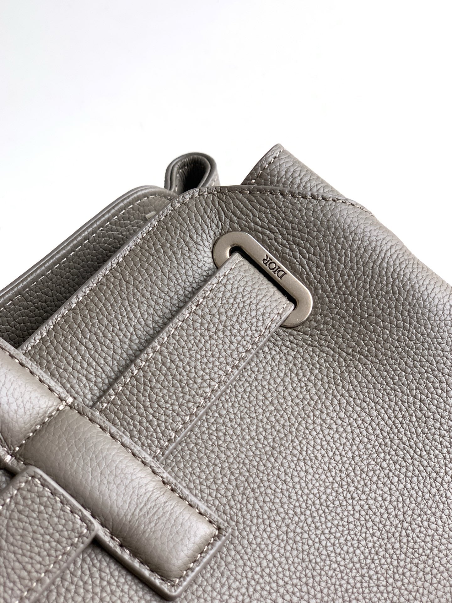 Dior men’s light gray leather bag close-up of metal D-ring and strap detail