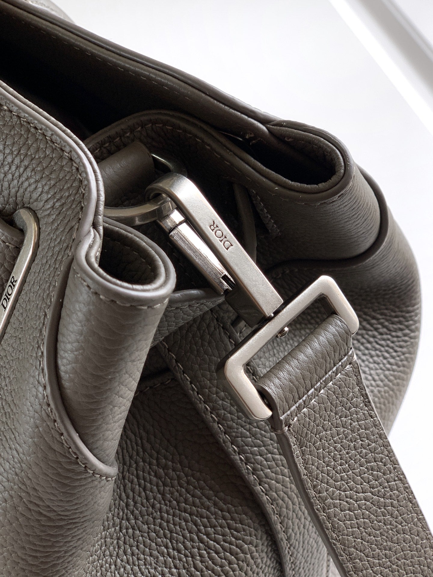 Dior men’s light gray leather bag close-up of clasp hardware and strap tabs