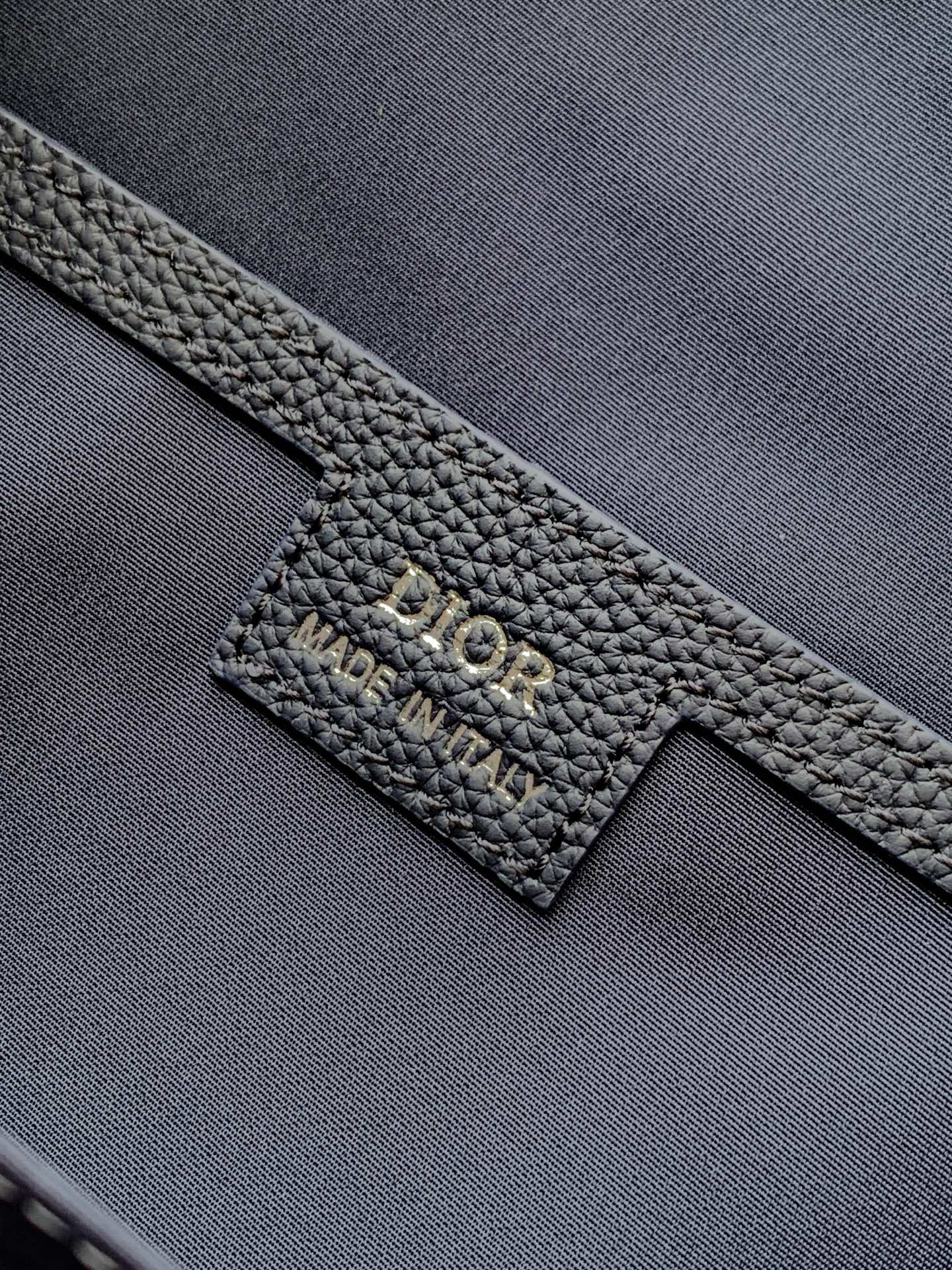 Dior logo leather patch on a dark blue textured bag strap