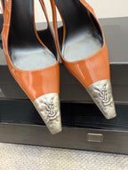 Women’s orange patent high-heel pumps with silver YSL emblem at pointed heels