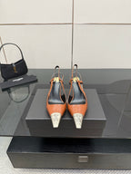 Women’s high-heel pumps with orange patent upper, black heel, silver YSL toe tips