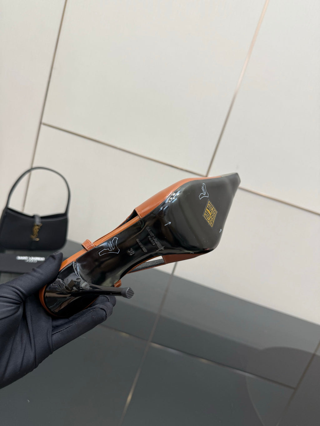 Women’s high-heel slingback pump close-up with orange patent and black side with YSL mark