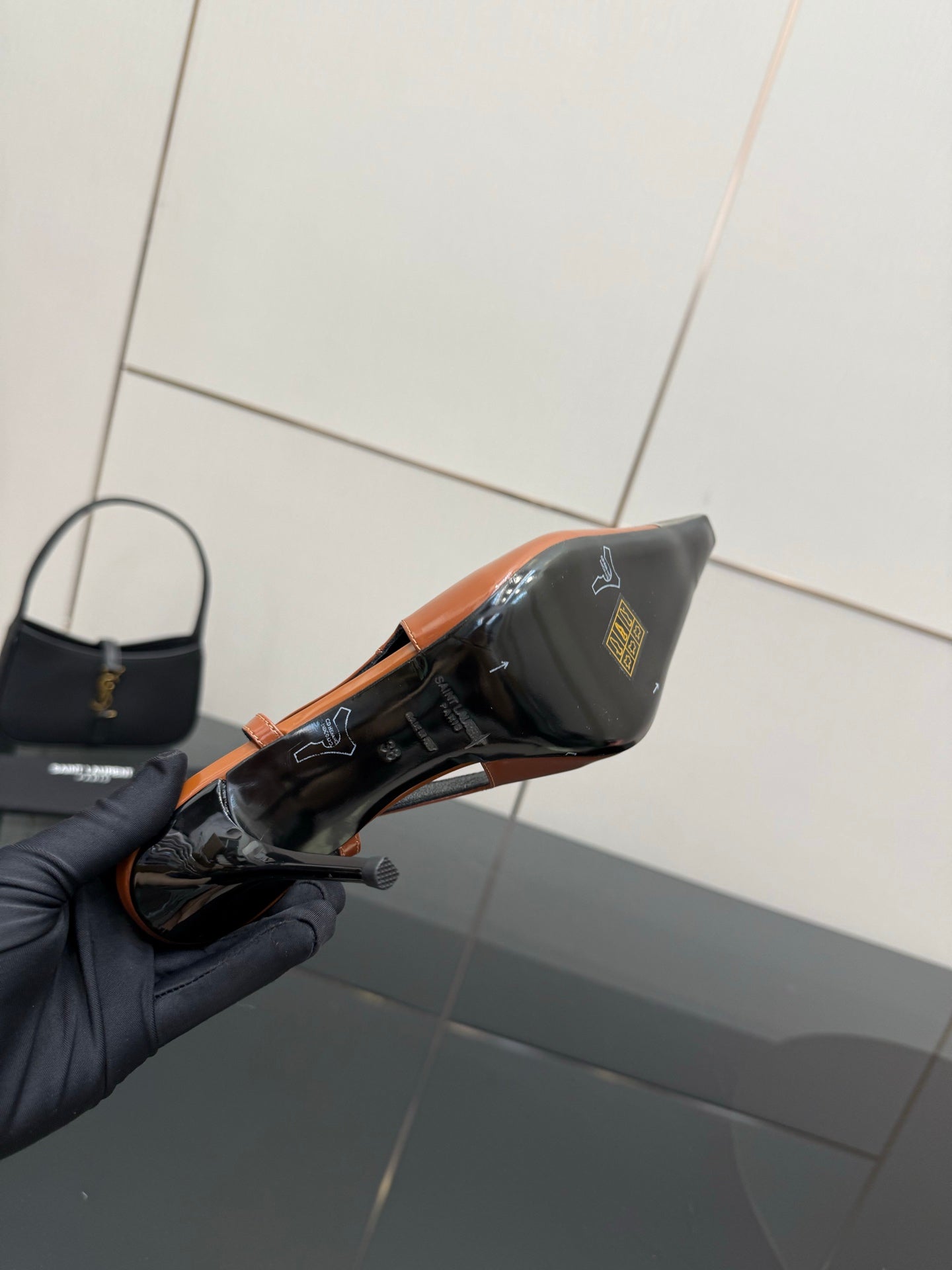 Women’s high-heel slingback pump close-up with orange patent and black side with YSL mark