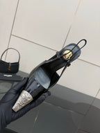 Women's YSL black pointed slingback pump with gold hardware, held in glove