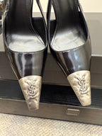 Women's YSL black patent pumps, close-up of silver toe caps and gold logo