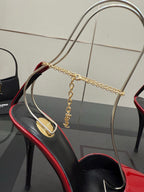 Women’s red patent high-heel shoe close-up with gold chain strap and gold emblem